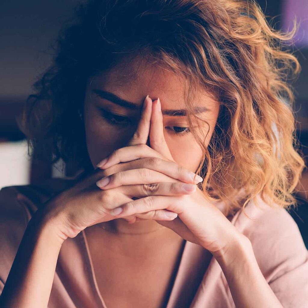 Young woman looking tired with hands on face