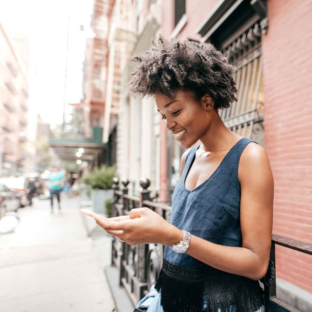 Young woman on city street looking at cell phone