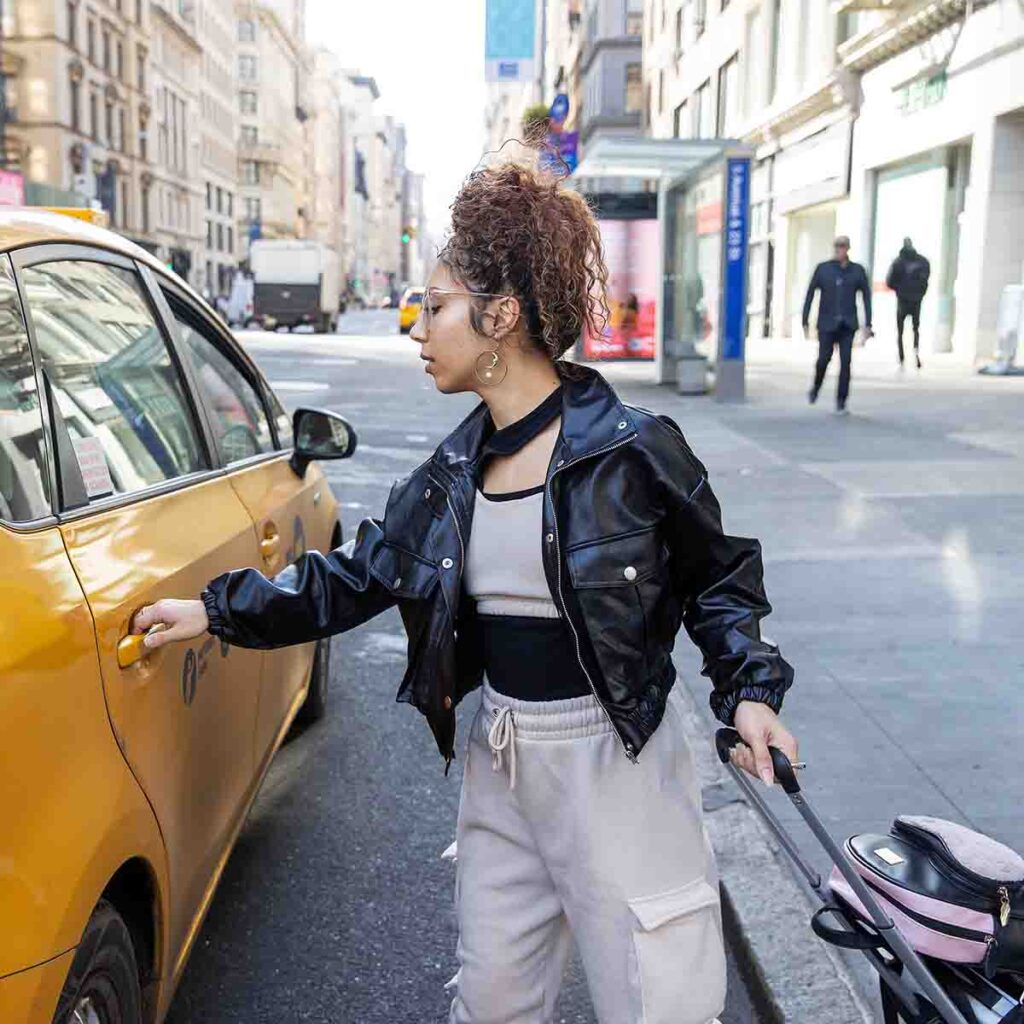 Young woman entering taxi on city street