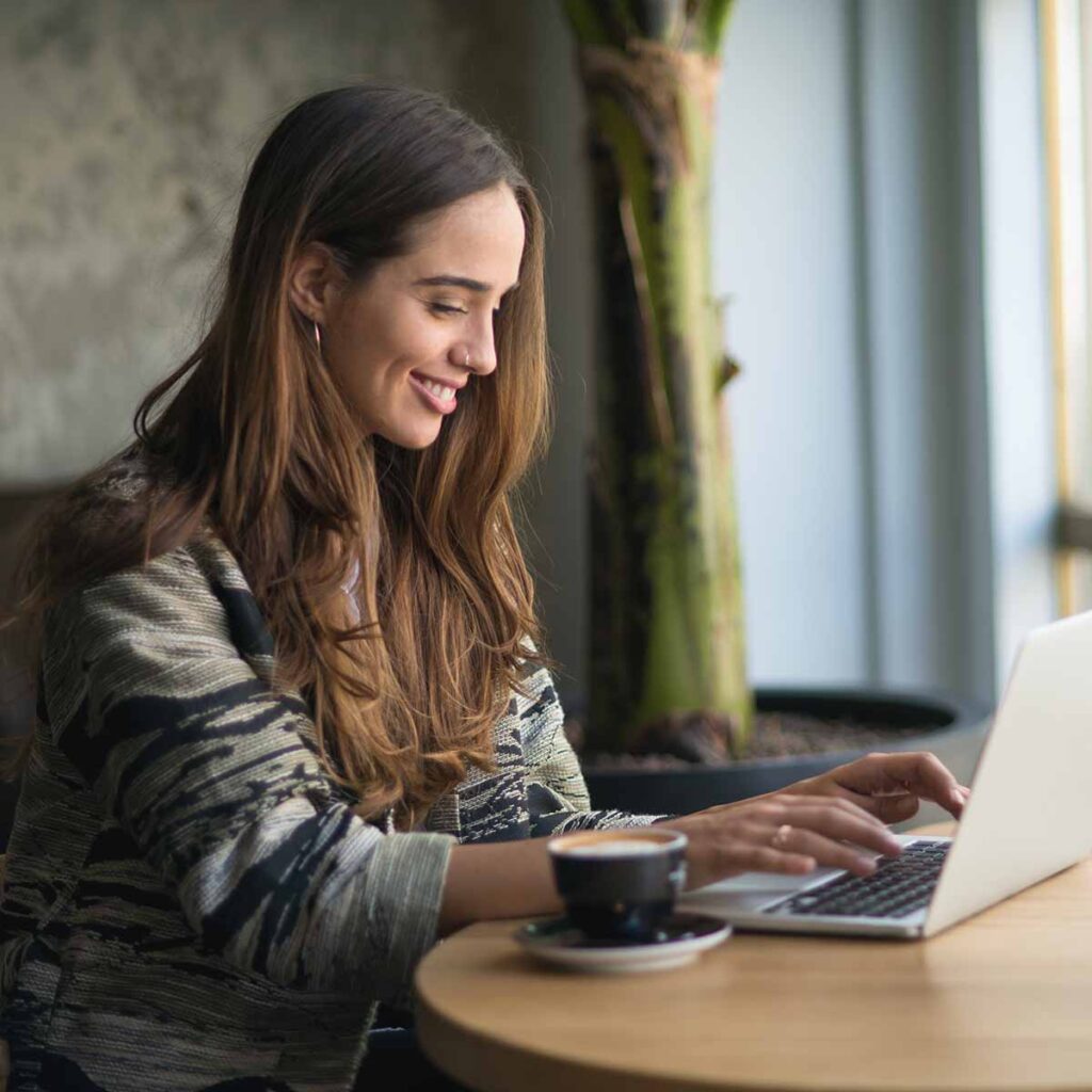 Young woman sitting at table using laptop