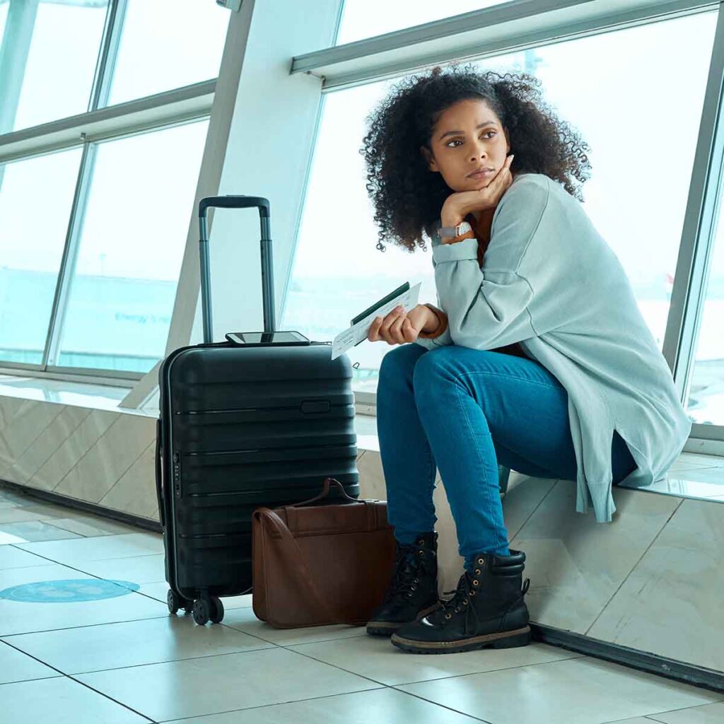 Young woman sitting at airport with luggage
